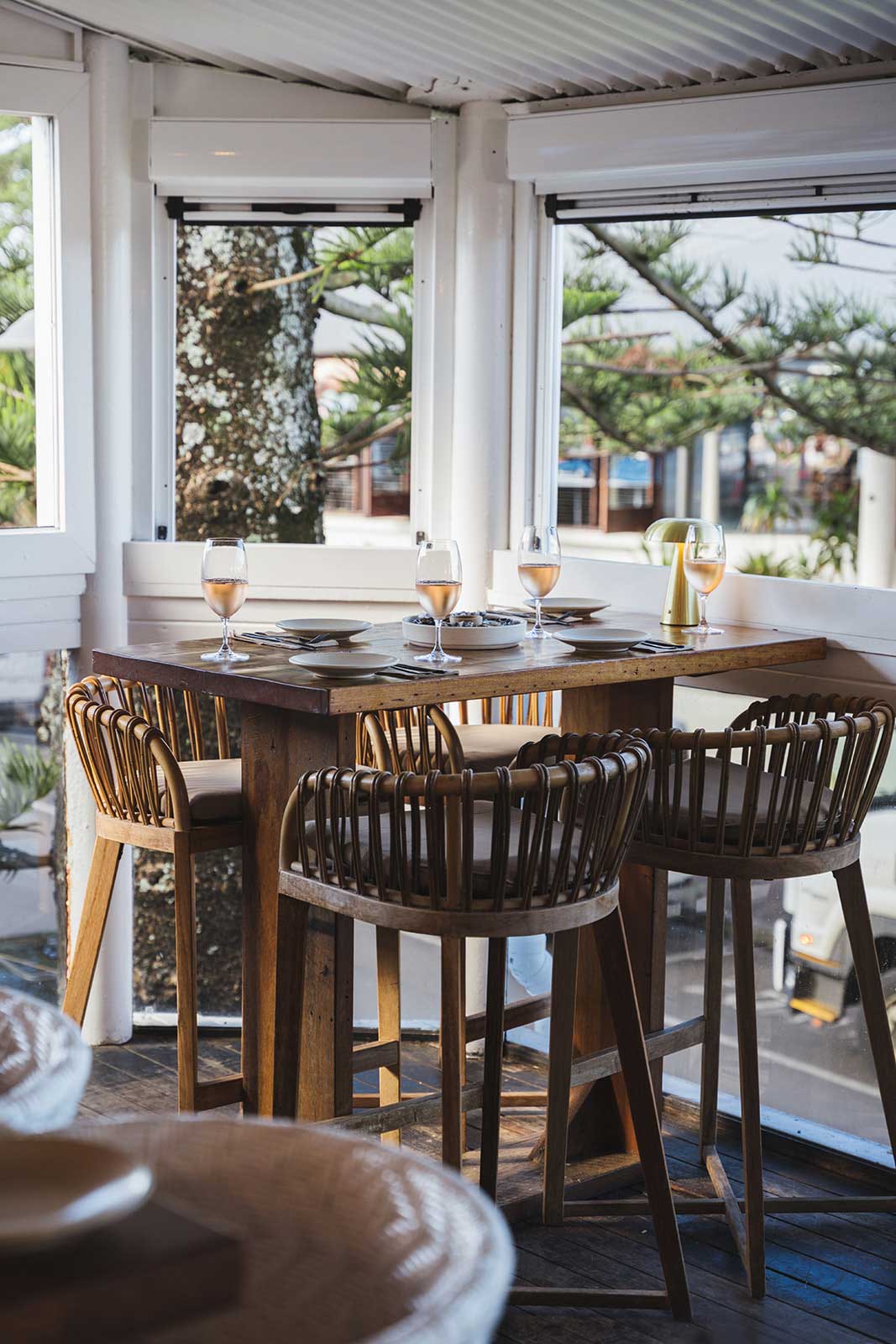 Loft Restaurant – Food and Drinks Set dining tables beneath pendant lights with views towards Main Beach at Loft Byron Bay